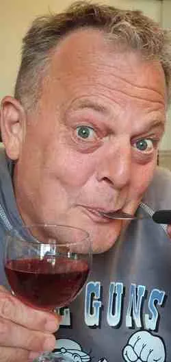 Vrolijke Robin heeft een vork in zijn mond en een glas wijn in zijn hand, want hij houdt van lekker eten en drinken. Hij gaat graag naar een restaurant.