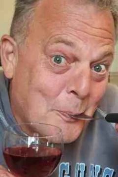 Vrolijke Robin heeft een vork in zijn mond en een glas wijn in zijn hand, want hij houdt van lekker eten en drinken. Hij gaat graag naar een restaurant.