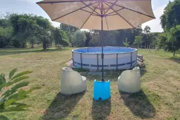 Zwembad in de grote tuin met zitje en parasol.